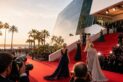 Illustration d’un tapis rouge à Cannes avec plusieurs silhouettes d’actrices de plus de 50 ans en robe de soirée montant les marches sous les flashs des photographes, devant le Palais des festivals.